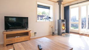 Ein Wohnzimmer mit Fernseher, Couchtisch aus Holz und Kamin.