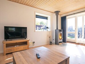 Un soggiorno con televisione, un tavolino in legno e un camino.