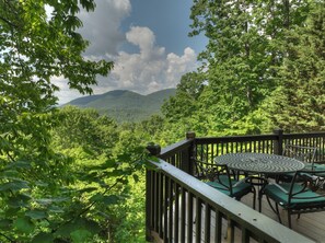 Relax on the deck with a panoramic view of lush mountains and dense foliage.