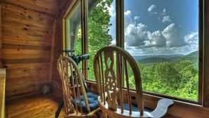 Habitación de cabaña de madera con un ventanal que ofrece vistas a un paisaje boscoso.