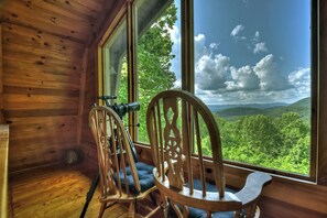 Relax in a serene cabin surrounded by a lush forest view, complete with a comfortable reading nook and stargazing telescope.