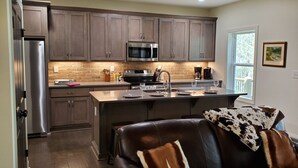 Una cocina moderna con armarios de madera oscura, electrodomésticos de acero inoxidable y una isla central con asientos.