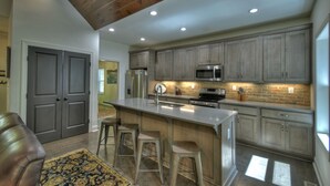 Una cocina moderna con una isla central, taburetes de bar y electrodomésticos integrados.