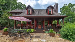 A two-story house with a porch, outdoor seating, and potted plants. - Experience the allure of Roost on the Ridge a pet-friendly sanctuary with hot tub, firepit, ping pong, spacious screen porch, and WiFi (Ellijay)