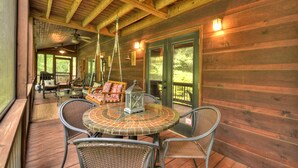 A wooden deck with wicker furniture, a round table, and a lantern.