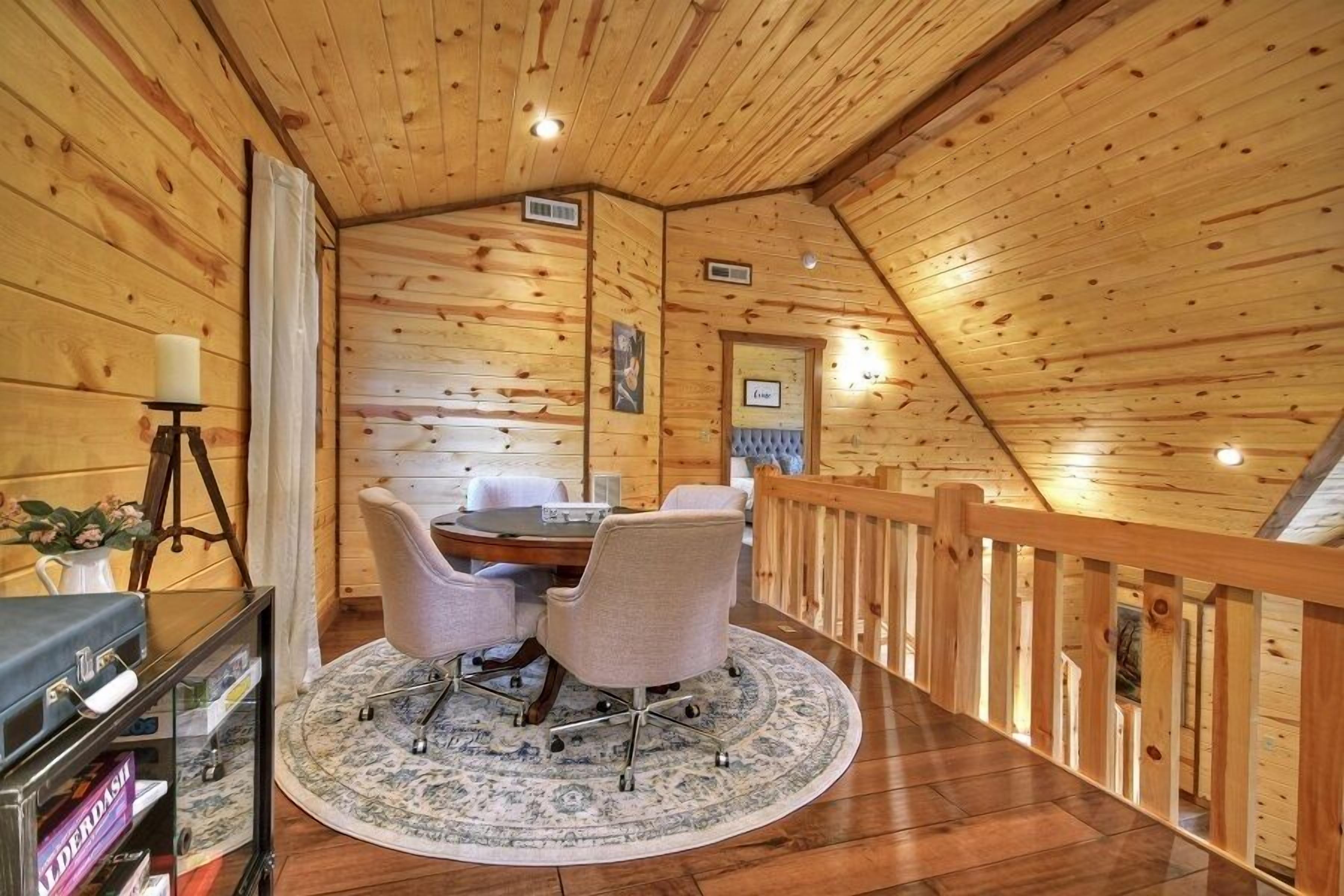 Un interior de madera con una mesa de comedor, sillas y un tapete redondo.