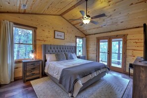 Une chambre à coucher avec un grand lit, des murs en bois, un ventilateur de plafond et une fenêtre avec des rideaux.