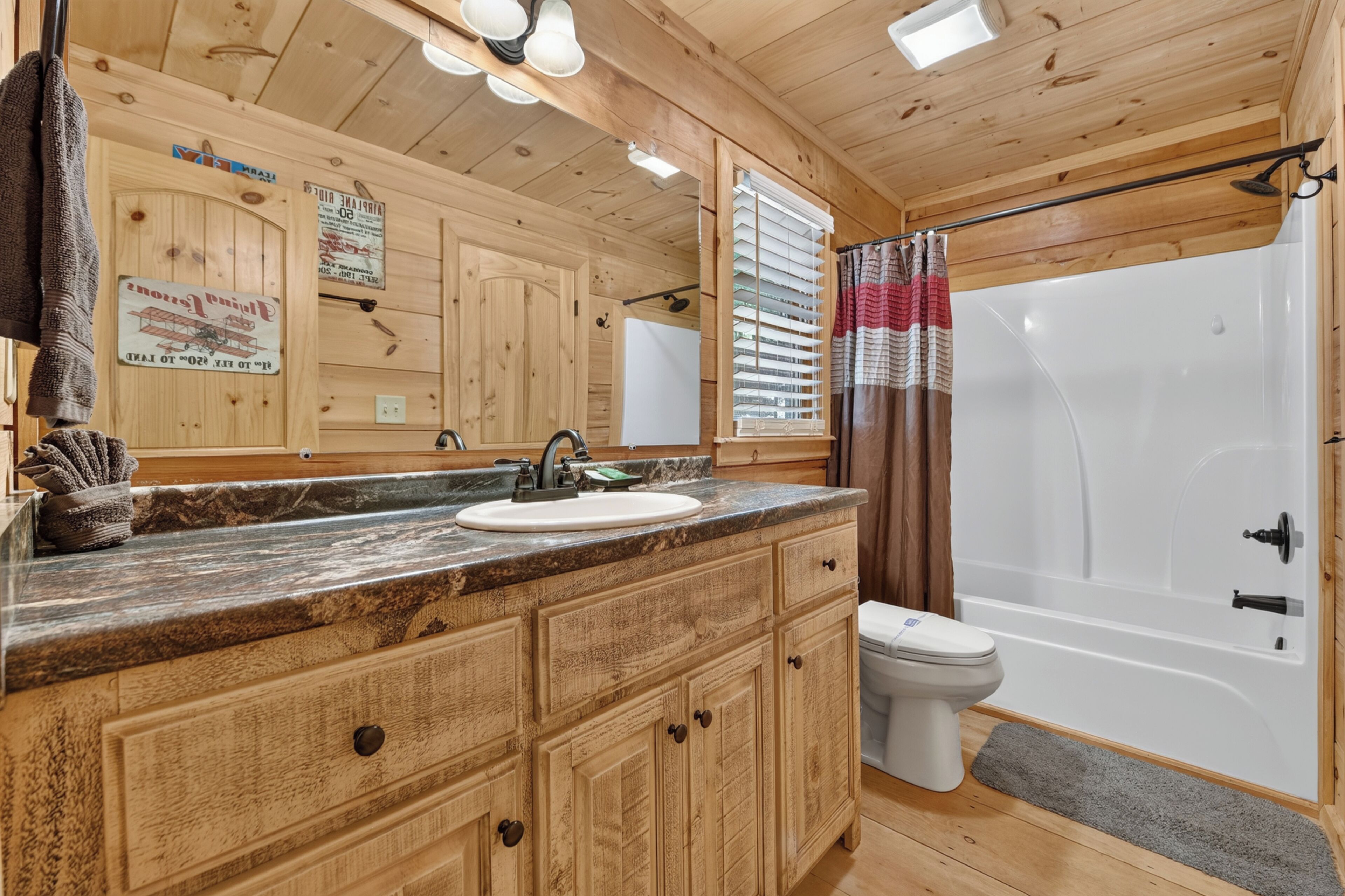 Een houten badkamer in een vakantiehuisje, met een wastafel, toilet en douche.