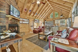A spacious living room with a fireplace, leather furniture, and wooden beams on the ceiling. - Up, Up and Away is pet friendly with a beautiful mountain view, hot tub, firepit, WiFi and fenced yard (Blue Ridge)
