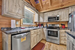 A kitchen with wooden cabinets, a stainless steel dishwasher, a microwave, a stove, and a refrigerator. - Up, Up and Away is pet friendly with a beautiful mountain view, hot tub, firepit, WiFi and fenced yard (Blue Ridge)