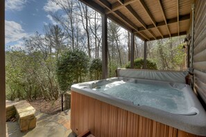 A hot tub under a wooden pergola with a forest view. - Ascend to serenity at Higher Ground! This pet-friendly haven offers majestic mountain views, a hot tub, firepit, WiFi, and unparalleled privacy. WiFi (Blue Ridge)
