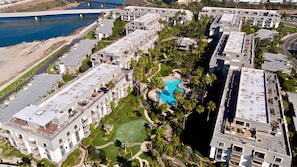 A high-rise hotel with multiple balconies, a central swimming pool, and a view of a river. - F14 Upper Cottage, Amazing oceanviews/Beachfront Luxury, Triple queen bunk, North Coast Village (Oceanside)