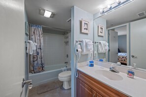 Ett badrum med badkar, toalett och handfat med spegel.
