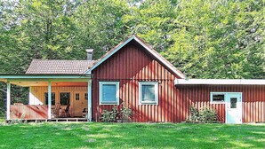 A red wooden house with a porch, a garage, and a small garden area. - 6 Person Holiday Home in Hastveda (Hästveda)