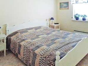 A bedroom with a bed, a bedside table, a lamp, and a window with plants. - 6 Person Holiday Home in Hastveda (Hästveda)