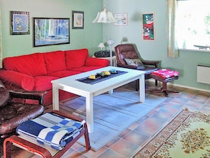 A living room with a red sofa, a white coffee table, a brown leather armchair, and a patterned rug. - 6 Person Holiday Home in Hastveda (Hästveda)