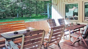 A wooden deck with a table and chairs, a bench, and a view of a wooded area. - 6 Person Holiday Home in Hastveda (Hästveda)