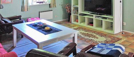 Una sala de estar con un mueble blanco para entretenimiento, una mesa de comedor y un sofá.