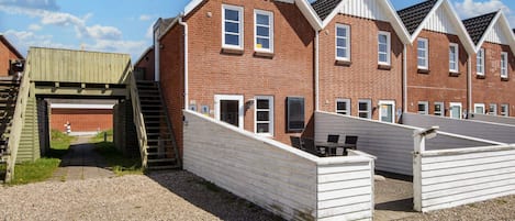 A row of brick buildings with a covered walkway and a gravel ground.