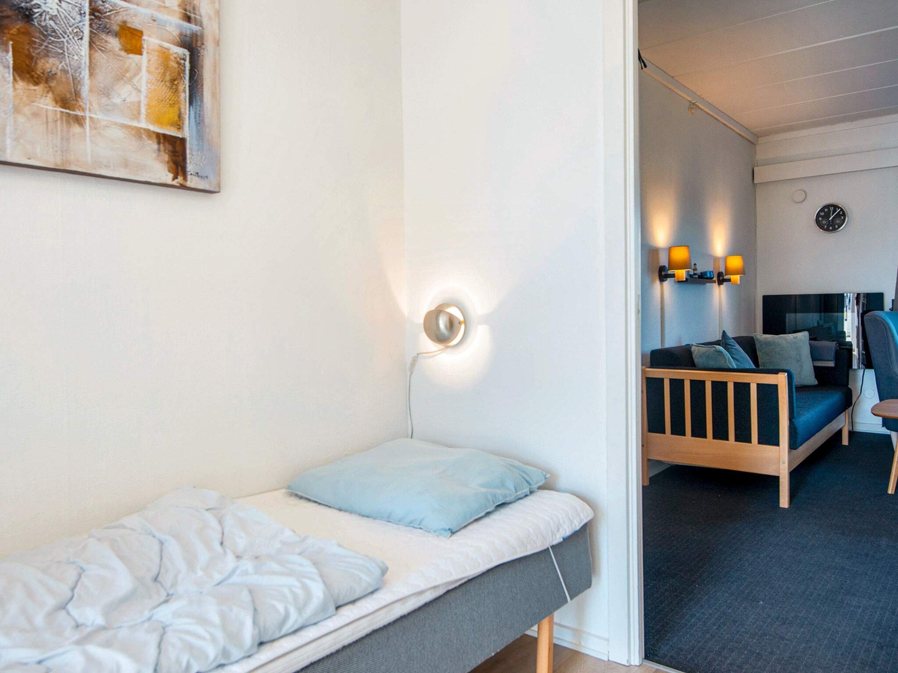 Un letto singolo con testiera, una lampada da comodino e una sveglia a muro.