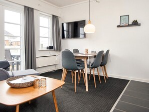 Un comedor moderno con una mesa, sillas, un televisor montado en la pared y un estante con un cuadro.