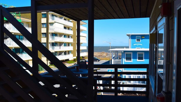 A view from a balcony overlooking a building with multiple floors and a blue structure in the background.