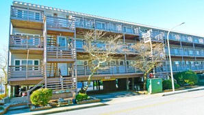 A multi-story hotel with balconies, a parking area, and a sign indicating a "Caution: Wet Floor" warning.