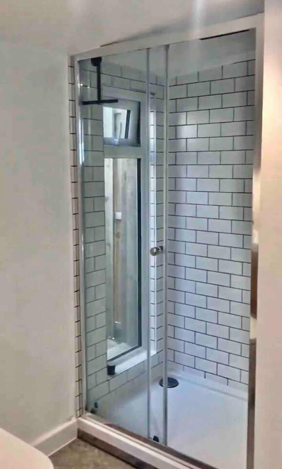 A glass-enclosed shower with a tiled wall.