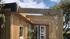 A wooden deck with a built-in seating area, a glass door leading to a covered patio, and a view of the surrounding landscape.