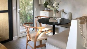 A modern kitchen with wooden beams, a dining area with a round table, and a sliding glass door leading to a garden.