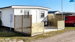 Een kleine, gelijkvloerse stacaravan met een omheind terras.