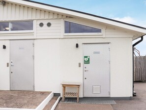 A building with a white exterior, two doors labeled "Disk & TVett" and "Hjärtstartare," and a small wooden bench outside.