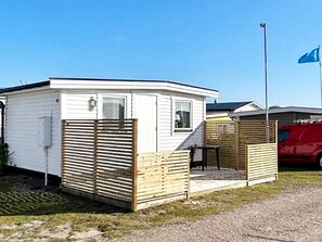 A mobile home with a fenced porch and a flagpole. - 3 Person Holiday Home in Falkenberg (Falkenberg)