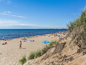 A beach with people sunbathing and swimming, a clear sky, and wind turbines in the distance. - 3 Person Holiday Home in Falkenberg (Falkenberg)