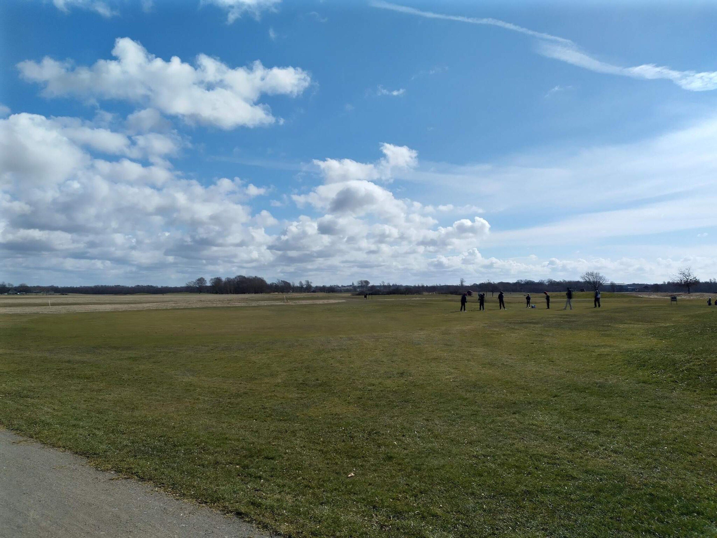 An open field with a clear sky and scattered clouds.