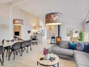 A modern living room with a sofa, dining table, chairs, a coffee table, and a fireplace.