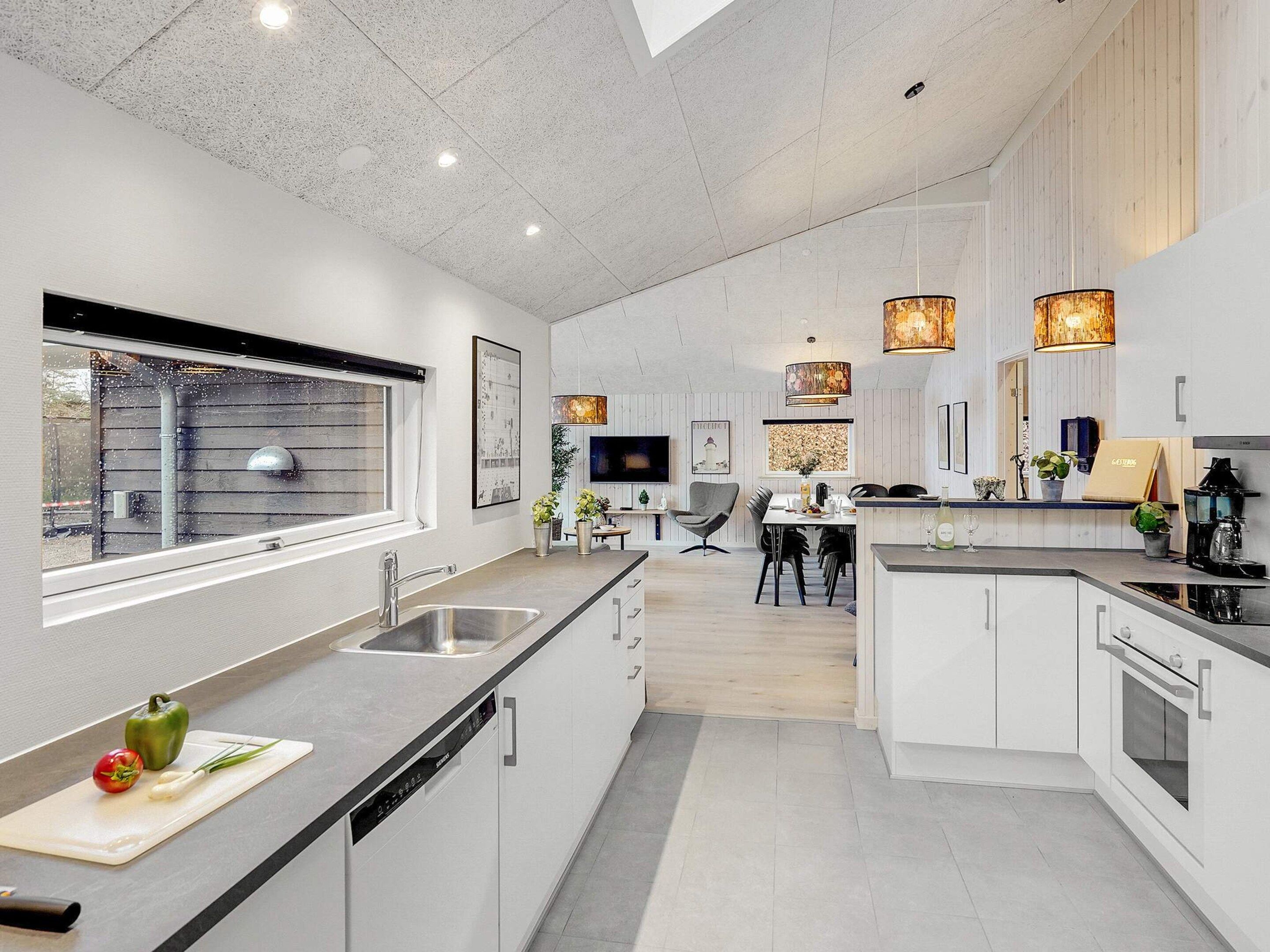 Una cocina moderna con una isla central, electrodomésticos integrados e iluminación colgante.
