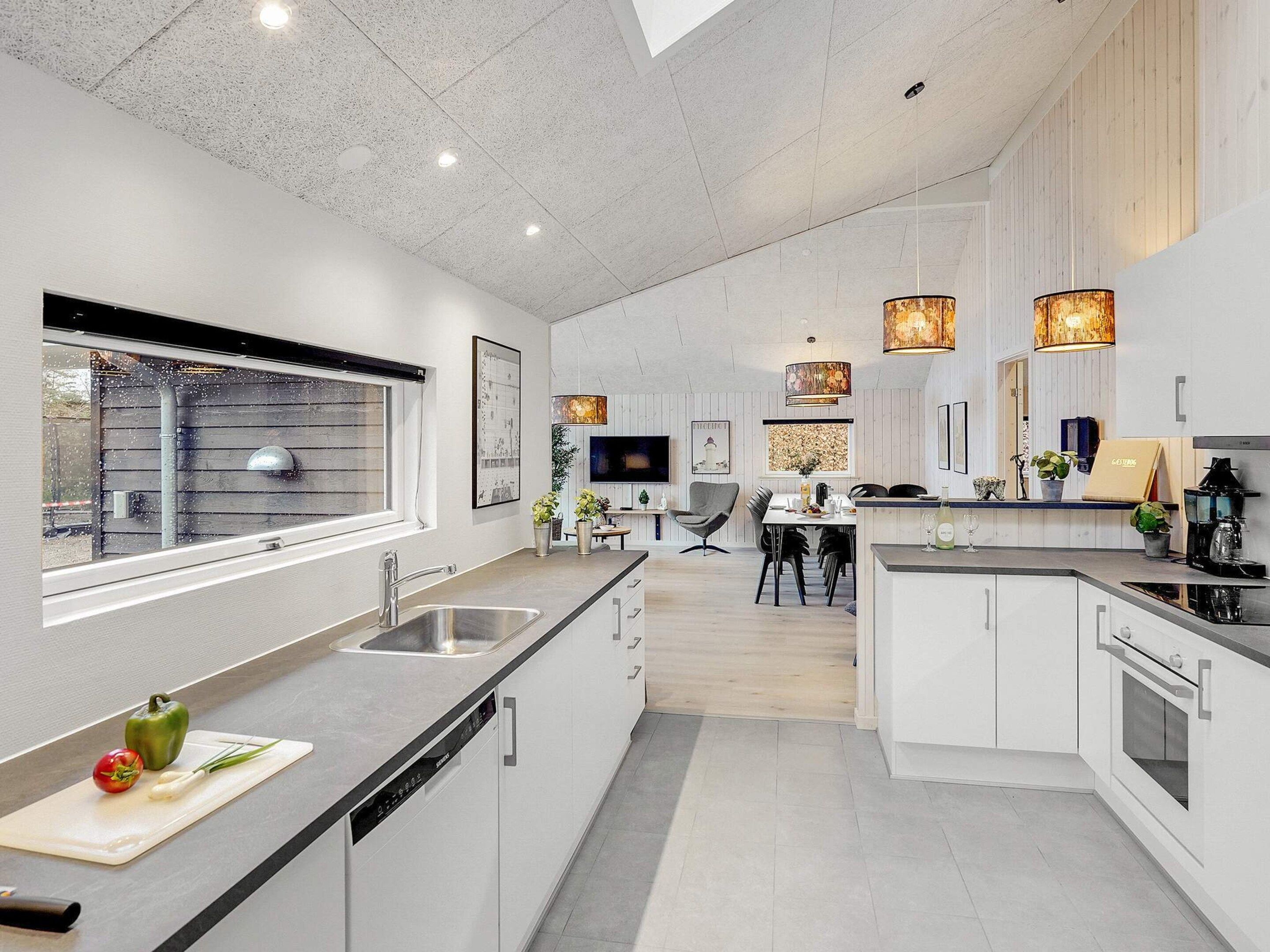 A modern kitchen with a central island, built-in appliances, and pendant lighting.