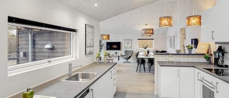 A modern kitchen with a central island, built-in appliances, and pendant lighting.