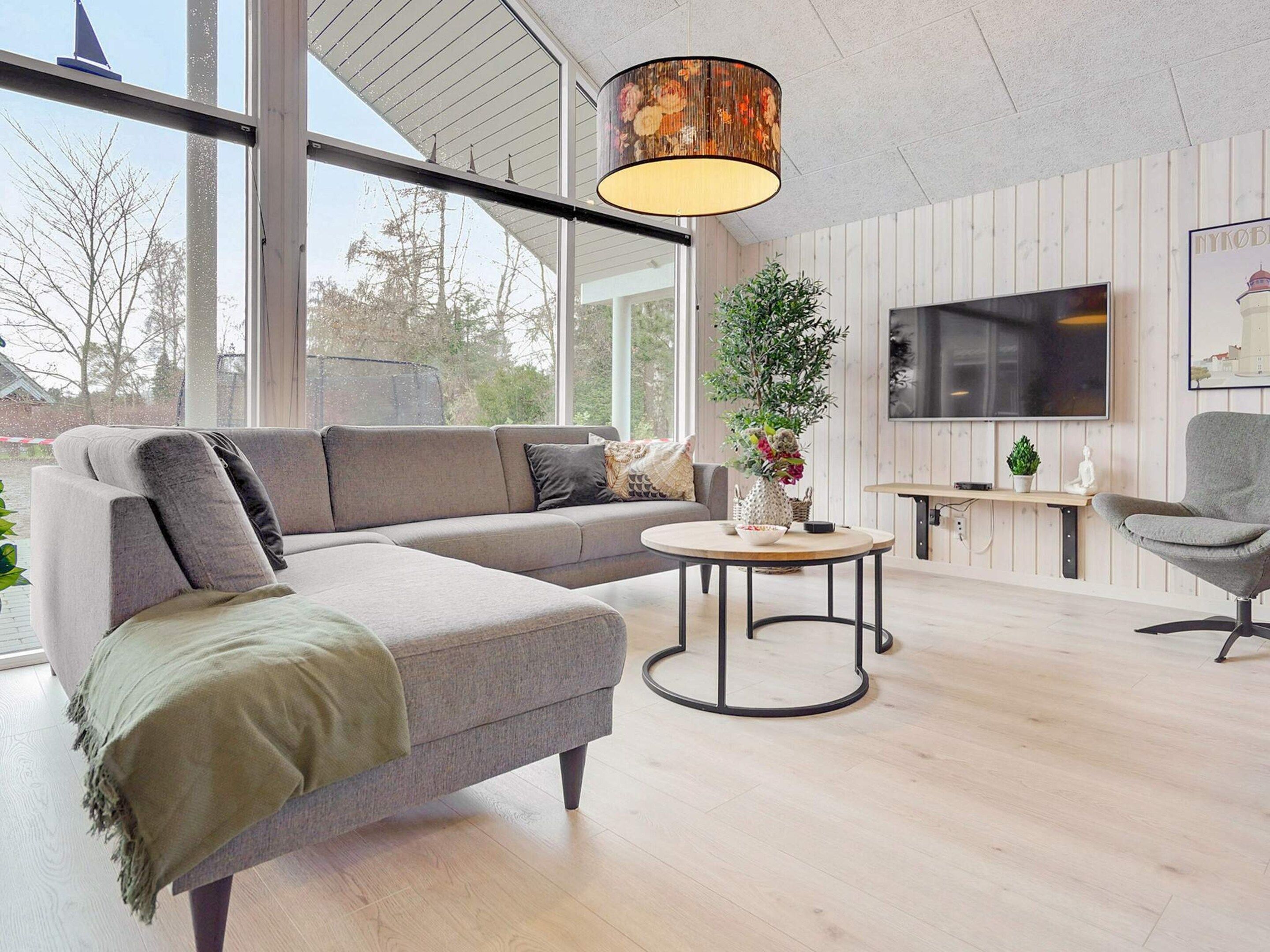 Ein modernes Wohnzimmer mit einer Eckcouch, einem runden Couchtisch und einem an der Wand befestigten Fernseher.