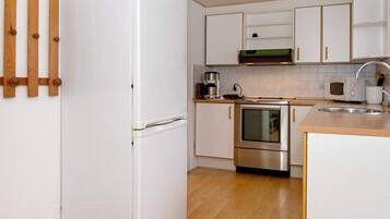 A kitchen with white cabinets, a stainless steel oven, a microwave, and a wooden floor.