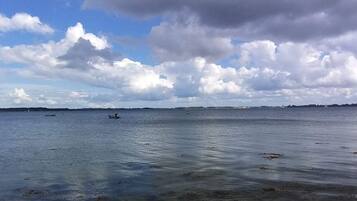 A coastal view with calm water, distant boats, and a partly cloudy sky.