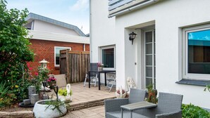 A patio area with a wicker table and chairs, a small garden with potted plants, and a brick wall. - 2 Person Holiday Home in Grasten (Grasten)