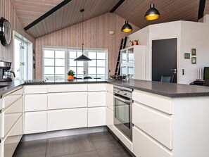 A modern kitchen with white cabinetry, a built-in oven, and pendant lighting.
