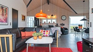 En moderne stue med en sort lædersofa, et hvidt bord og rød løber.