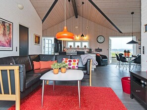 A modern living space with a black leather sofa, a white table, and red carpeting. - 4 Star Holiday Home in Juelsminde (Juelsminde)