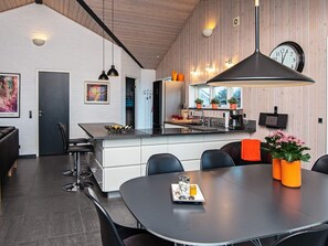 A modern kitchen with a central island, a dining area with a round table, and a large pendant light.