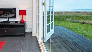 Una habitación con una televisión, una lámpara roja y un ventanal grande con vistas a una zona verde.