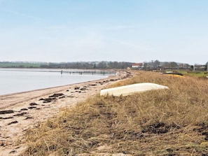 A beach with a sandy shore, a concrete structure, and a distant view of buildings.