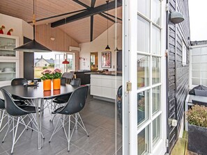 A modern kitchen with a dining area, featuring a large table, chairs, and a view of the outdoors.